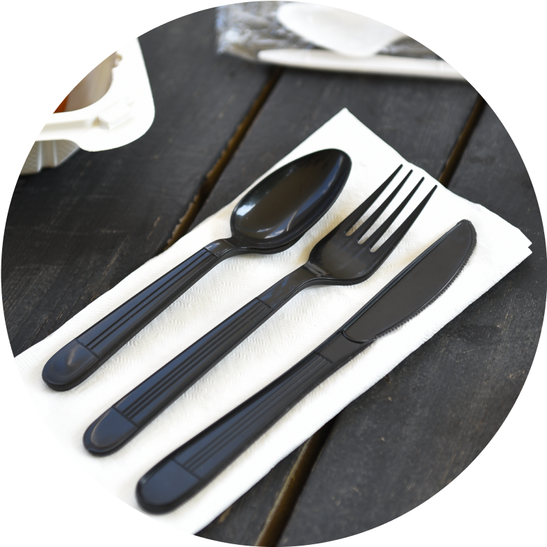 Black disposable plastic cutlery set with spoon, fork, and knife on a napkin, perfect for restaurants and catering